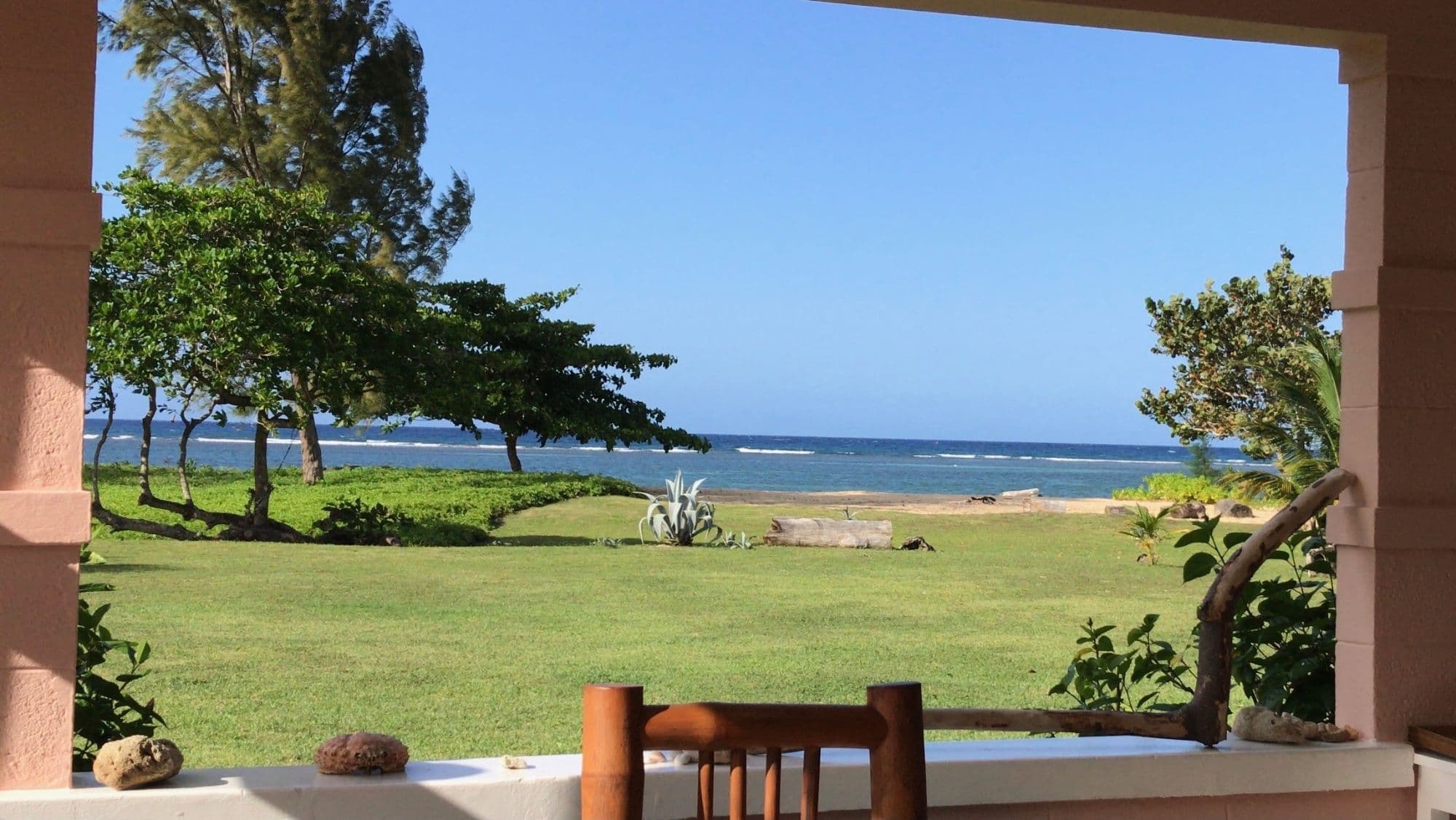 The veranda posts framing the lawn and the sea